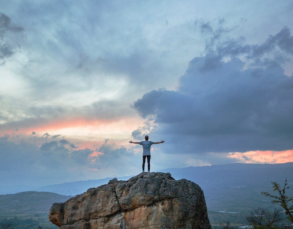 man standing on top of rock mountain during golden hour