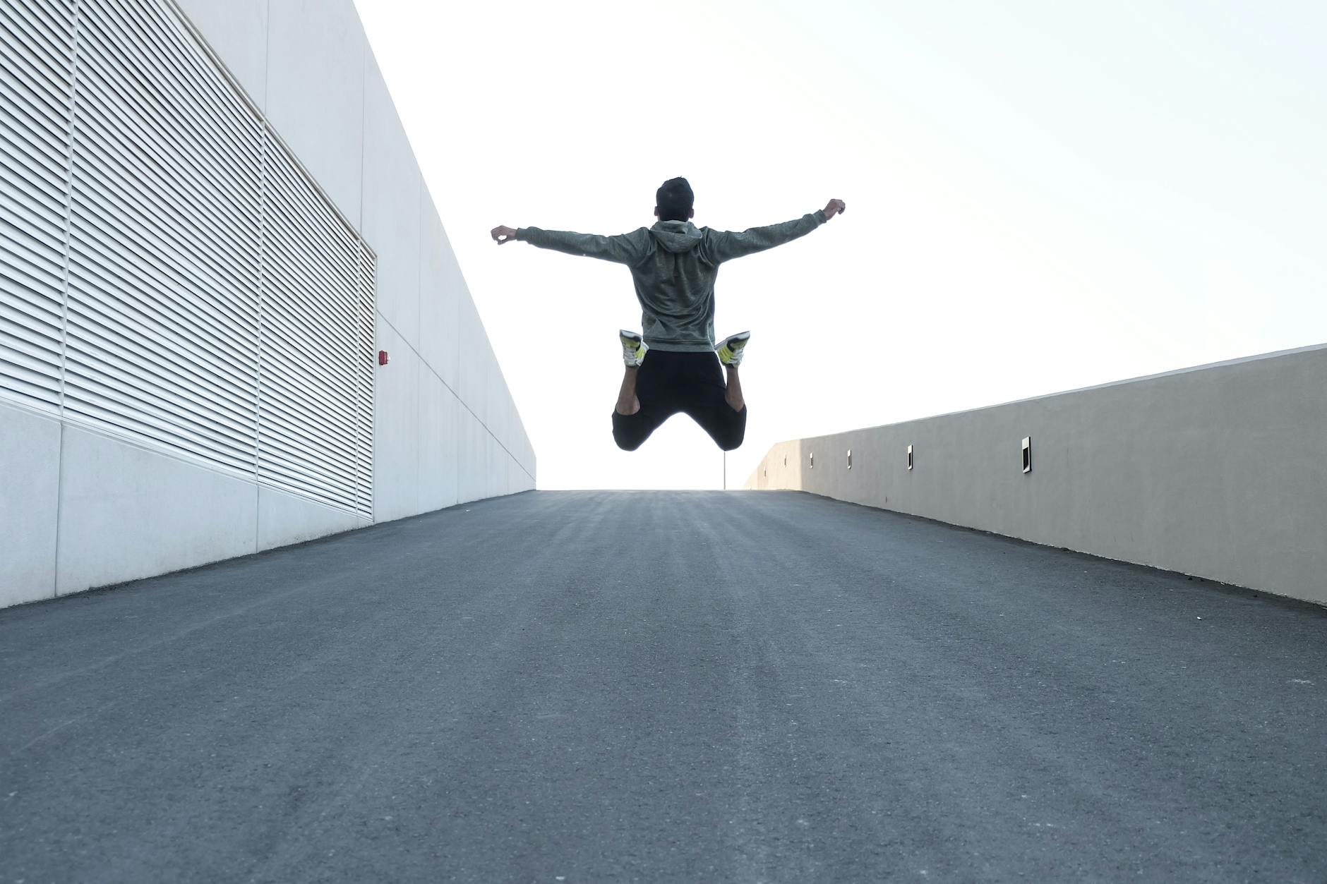 man in gray hoodie jump with open arms