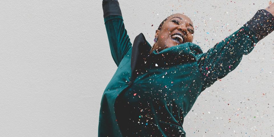woman in green jacket raising her hands